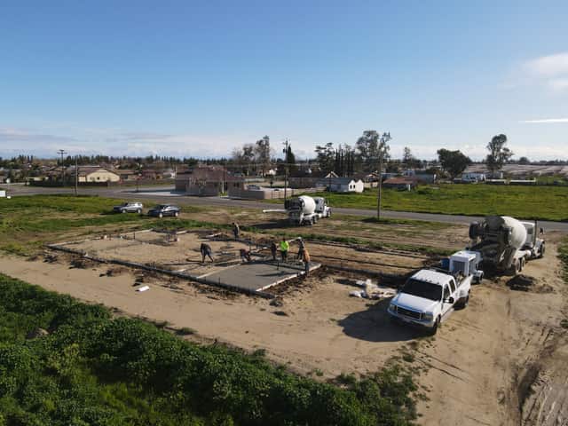 Aerial view of a crew pouring a concrete foundation with two cement mixer trucks beside the lot