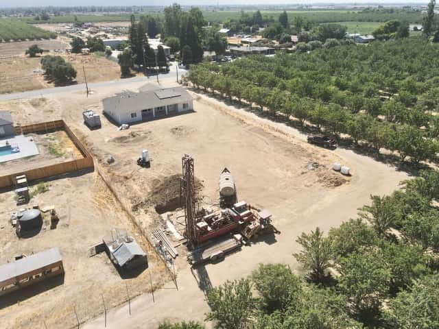 Aerial view of an Almond Grove Homes jobsite with a well drilling rig beside an almond orchard