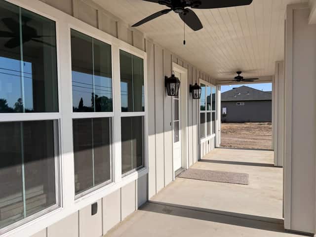 Covered front porch with tall windows, a beadboard ceiling, and a ceiling fan