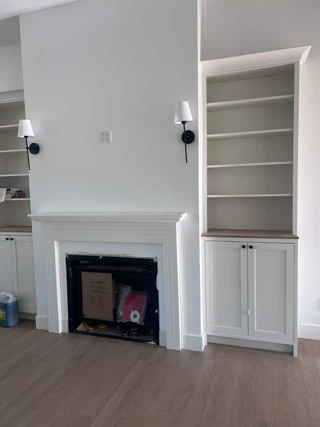 Fireplace with a white mantel flanked by built in shelving