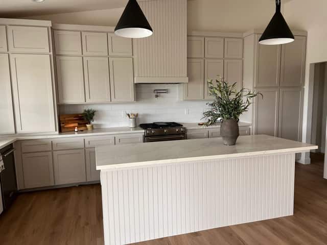 Kitchen with a beadboard range hood, a gas range, and a waterfall edge island