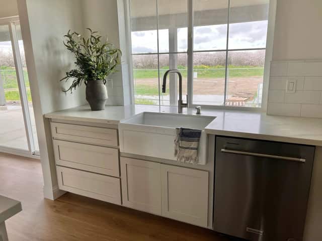 Farmhouse sink set under a window looking out over an open Central Valley field