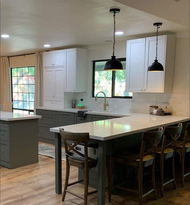Remodeled kitchen with green lower cabinets, white uppers, and an island with counter seating