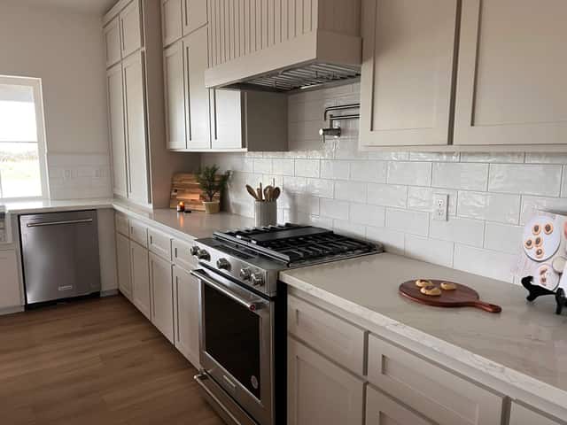 Kitchen run with a stainless steel range, subway tile backsplash, and quartz countertops