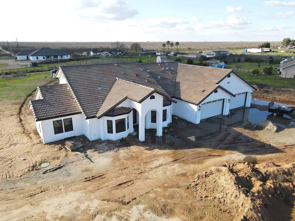 Aerial view of a newly built single story custom home on a rural Madera lot with the exterior stucco complete
