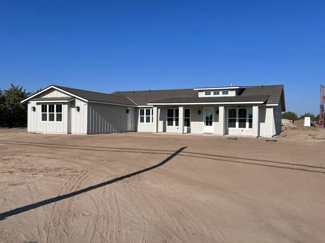 Completed white board and batten farmhouse style home we built. Opens our custom home building page.