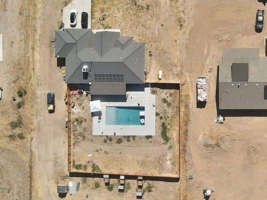 Close aerial view of a completed Almond Grove Homes pool and deck beside the finished house, on a Madera area jobsite