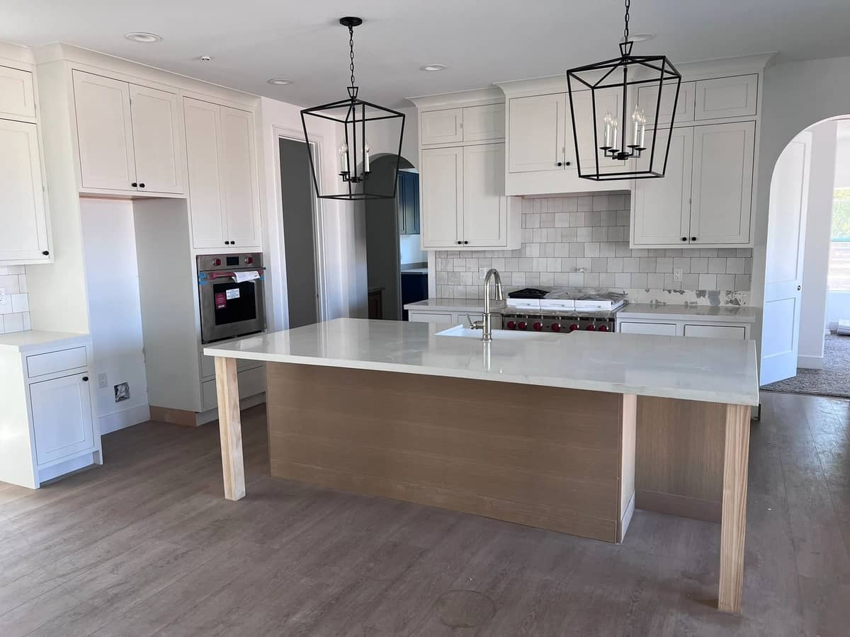 Finished kitchen with a long island, lantern pendant lights, and double wall ovens