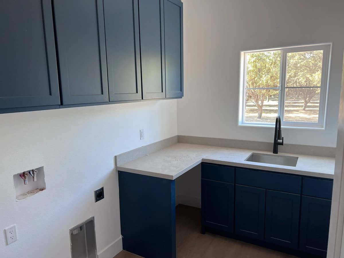 Utility room build out with navy shaker cabinets, quartz counters, and a farmhouse style sink